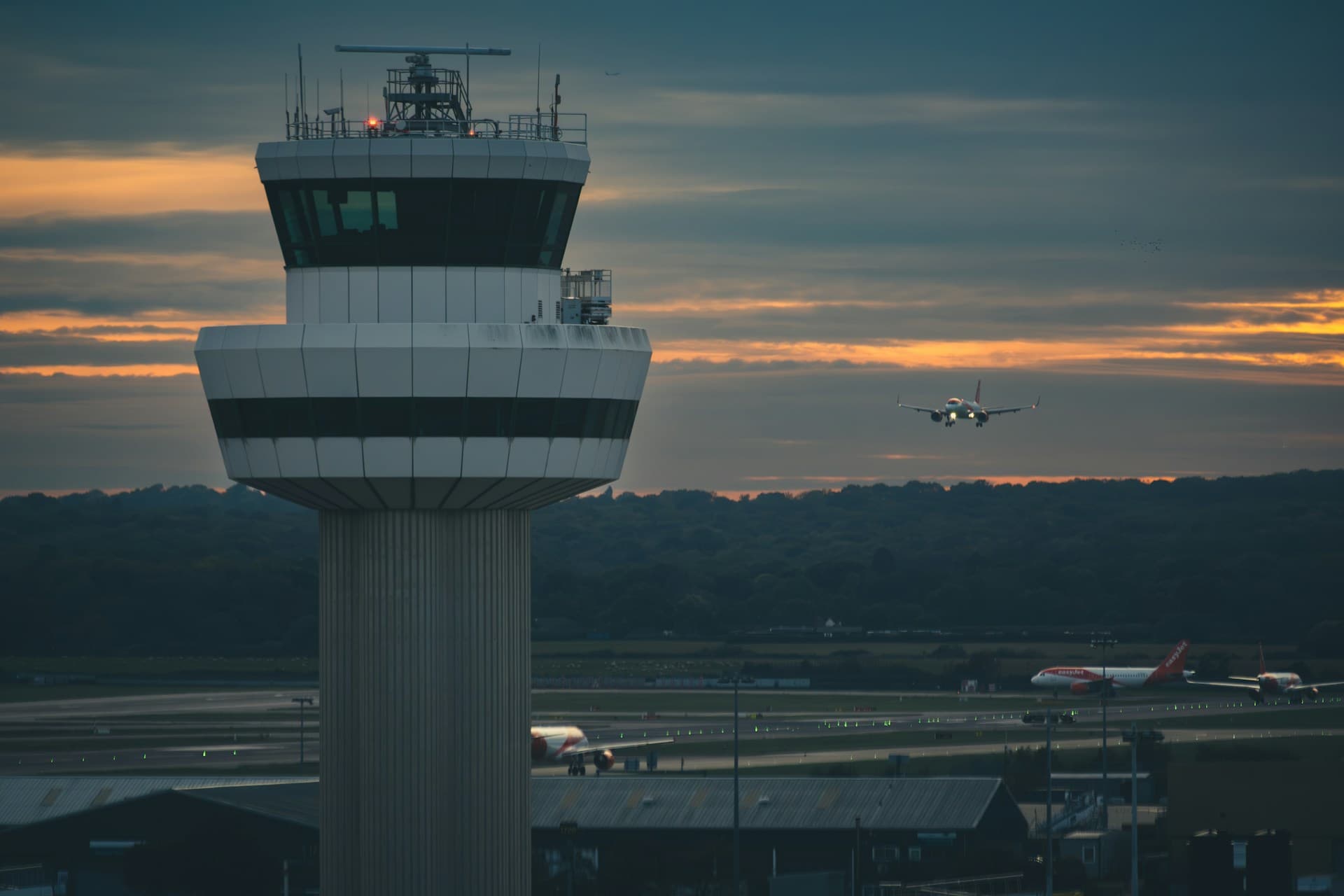 Air traffic control tower with aircraft approaching at dusk